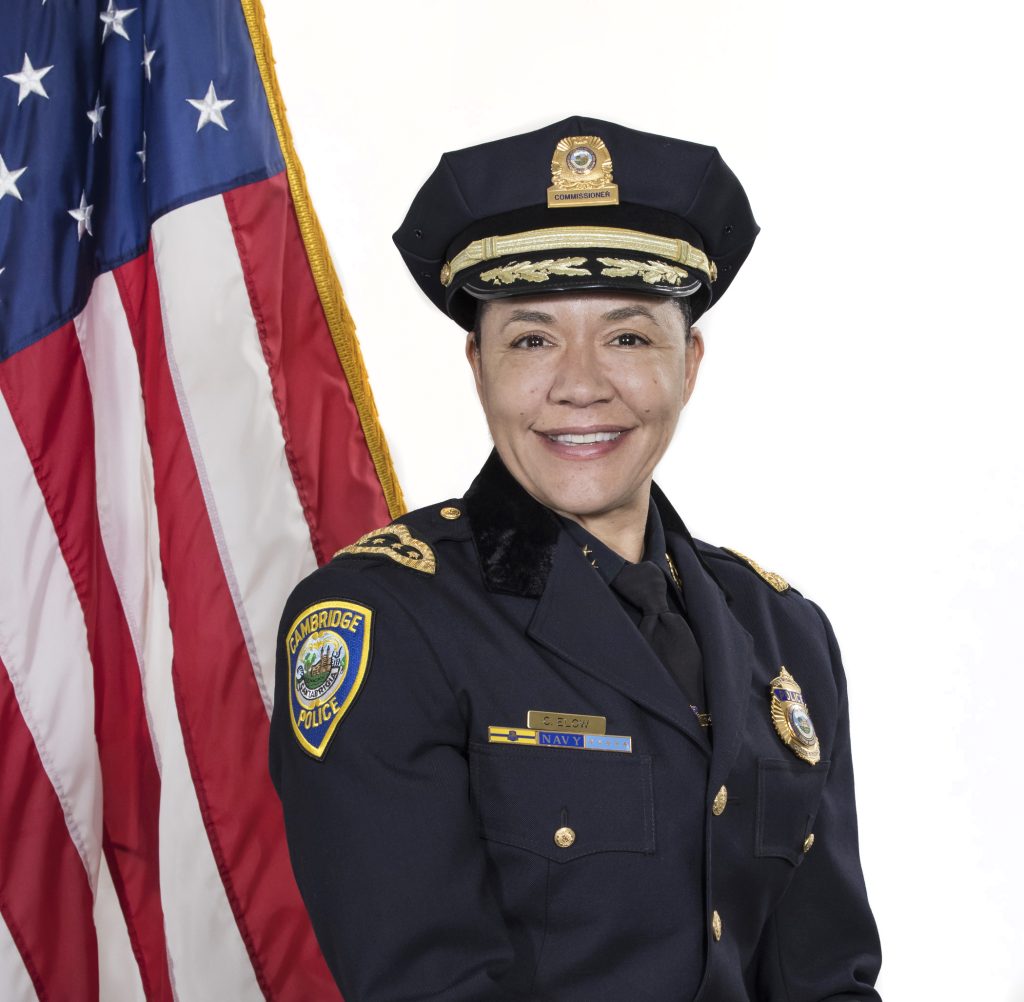 woman in police uniform smiling in front of an american flag